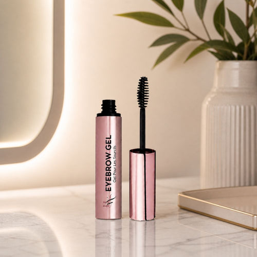 Eyebrow gel with applicator on a marble surface with a plant in the background